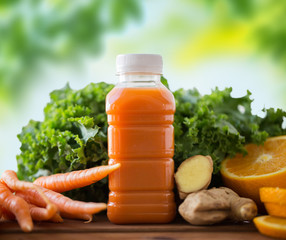 healthy eating, food, dieting and vegetarian concept - bottle with carrot juice, fruits and vegetables on wooden table over green natural background