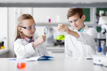 education, science and children concept - kids or students with test tube and magnifier studying che