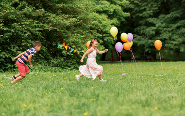 friendship, childhood, leisure and people concept - happy kids or friends playing tag game at birthday party in summer park