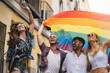 © ADDICTIVE STOCK - Group of gay friends with a gay pride flag on the street of Madrid city