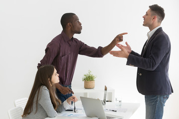 Angry multiethnic colleagues disputing during business meeting, African American worker blaming Caucasian partner for mistake, coworkers disagree on project, argue at company briefing in office