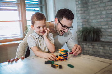 Father and adorable son playing with education game, family fun at home concept