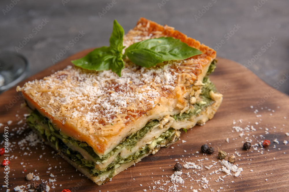 Lasagna with spinach on wooden board, close up