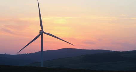 Wall Mural - scenic landscape view of wind turbines blades rotating with pink purple twilight sky on background fiery sunset kinetic energy electricity ecology lifestyle peaceful rural area eco-business trend