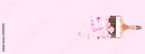 Paint brush and pink flowers of violet with confetti on pink background. Crea...