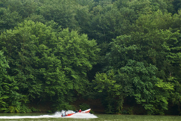 Tourist boat with traveling peoples at green forest and the lake water, beauty in nature. 