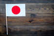 © 9dreamstudio - Japanese flag concept. small flag on dark wooden background top view copy space