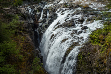 beautiful waterfall rushing into the gap of two giant rocks in the forest