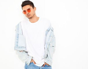 Portrait of handsome young model man dressed in jeans clothes in sunglasses posing on white background. Isolated