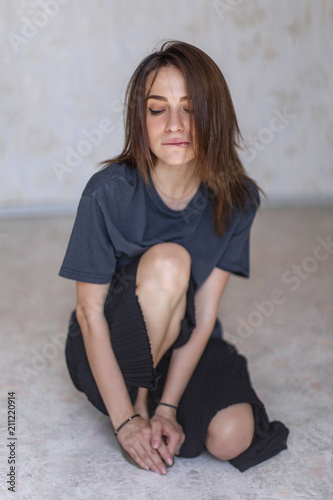 Fotografia attractive woman wearing blue t-shirt and black pants while sitting on floor in