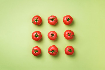 Wall Mural - creative pattern of red tomatos on green background. top view. copy space. minimal design. vegetaria