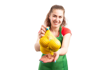 Wall Mural - Woman supermarket or retail worker offering bag of lemons.