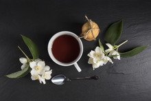  A Cup Of Tea With Jasmine Flowers On A Dark Background. Top View.