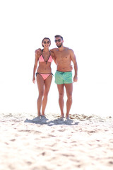 Young couple holding hands and walking on beach.