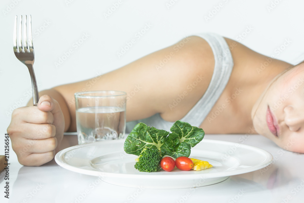 unhappy asian women is on dieting time looking at broccoli on the fork. girl do not want to eat vegetables and dislike taste of broccoli. - obrazy, fototapety, plakaty 