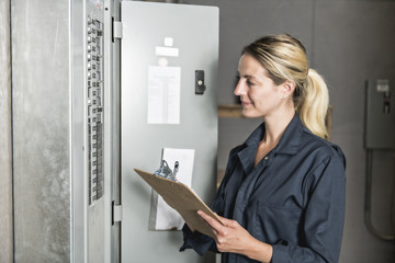 Woman Technician servicing at work on electric room