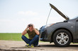 © snedorez - Image of young man sitting next to broken car with open hood