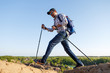 © snedorez - Photo of young tourist man with walking sticks walking in mountainous area