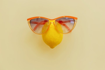 yellow lemon in orange sunglasses on pastel yellow paper, trendy flat lay. summer vacation idea. juicy fruit eat and diet concept. pop art style. creative minimalism . space for text