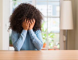 Sticker - African american woman at home with sad expression covering face with hands while crying. Depression concept.