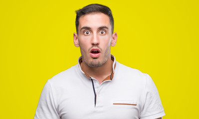 Canvas Print - Handsome young casual man wearing white t-shirt scared in shock with a surprise face, afraid and excited with fear expression