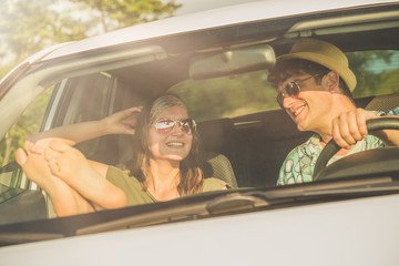 Young beautiful couple traveling together and enjoying in their car.