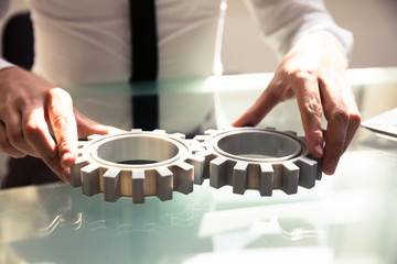 Close-up Of A Person Connecting Two Gears