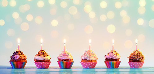 Row Of Colorful Cupcake With Candles And Bokeh Lights