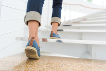 Young Adult Woman Walking Up The Stairs With Sun Sport Background.