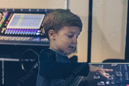 Fotografía Little DJ adjusting sound on audio mixer in music studio.