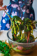 Woman hands holds with spoons cooked boiled beetroot leaves and sprouts as part of Georgian traditional food meal pkhali. Cooked as appetizer. Vegan vegetarian healthy food.