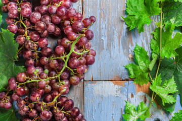 Poster - Grapes fresh red arrangement with green leaves overhead on old rustic blue wooden table in studio