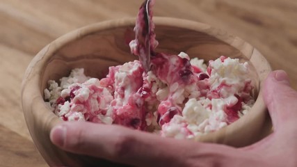 Wall Mural - Slow motion closeup mixing cowberry jam with cottage cheese in wood bowl