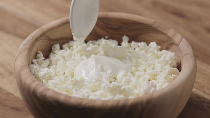 Sticker - Slow motion closeup mixing sour cream with cottage cheese in wood bowl