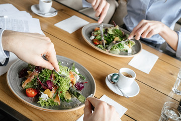 Businesspeople having business lunch at restaurant sitting eating salad close-up