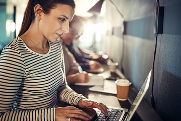 Wall Mural - Smiling young designer sitting with office colleagues using a la