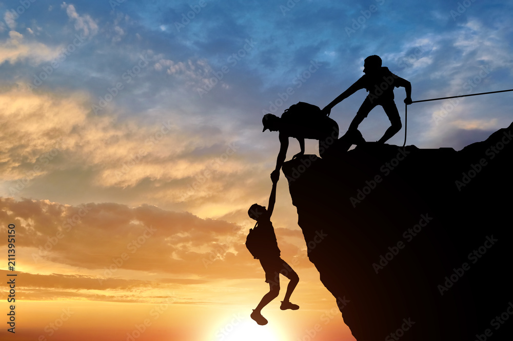 Person Rescuing Another Person Silhouette of three male climbers rescuing another male climber pulling ...