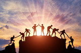 Fototapeta Tęcza - Silhouette of climbers who climbed to the top of the mountain thanks to mutual assistance and teamwork