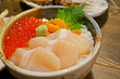 Tasty and delicious Sushi Donburi or Japanese rice bowl topped with various of fresh raw sashimi seafood.. Hotate(scallop), Ikura(salmon roe) and Uni(Sea Urchin) with Wasabi. Close up. Healthy Eating.
