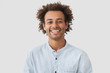 © wayhome.studio  - Happy mixed race male student with Afro hairdo shows white teeth, being in good mood after classes as going to have date with female groupmate, stands against white background. Positiveness concept