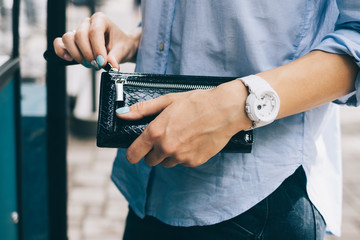 Young woman closing zipper on her wallet standing outdoors