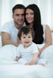© ASDF - Happy couple and son sitting in bed
