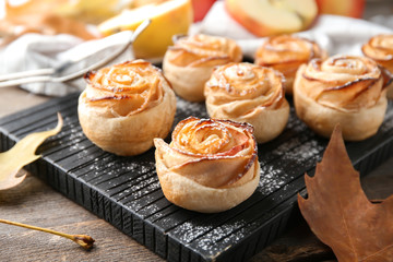 Wall Mural - Wooden board with apple roses from puff pastry on table, closeup