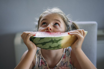 Little girl eating watermelon on the table