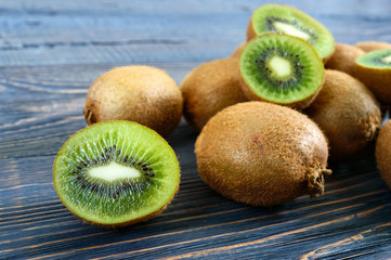 Wall Mural - Fresh ripe kiwi fruit on a wooden table. Whole and half-cut fruits. Tropical fruit. Healthy food.