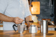 man in the morning Making coffee on a wooden table with a geyser retro coffee maker.
