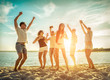 © Andrii IURLOV - Friends funny dance on the beach under sunset sunlight. Sunny day