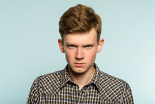 Angry Threatening And Intimidating Man. Disrespect And Arrogance. Portrait Of A Young Guy On Light Background. Emotion Facial Expression. Feelings And People Reaction Concept.