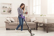 Young woman cleaning house with vacuum cleaner