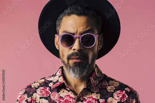 Fotografia Portrait of a trendy man with silver beard, sunglasses and hat, isolated on pink